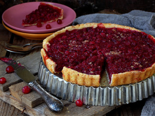 Tart, cake with red cranberries and walnuts on wooden background. Berry pie. Space for text