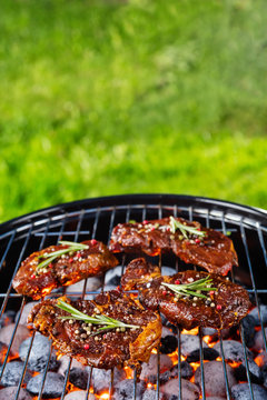 Beef steaks on the grill grate with fiery coals