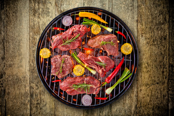 Top view of fresh meat and vegetable on grill placed on wooden floor