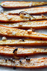 Roasted spring carrots on parchment with garlic, pepper peas and coriander on baking sheet. Selective focus