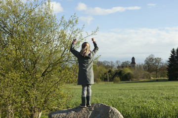 young girl raising arms in mood of happiness
