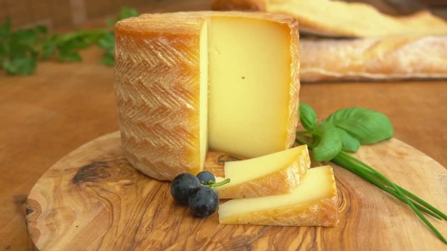 pasteurised sheeps milk cheese made in French Basque region with a piece cut out on a wooden table