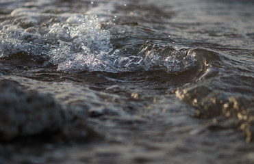 Wave splash of the water in the sea with specks and reflections during high tide time, abstract background or texture