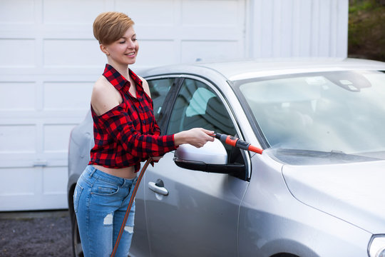 A woman with dark short hair wash a car