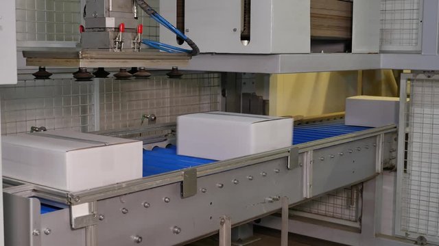 Boxes being picked by a robotic arm in a bakery factory for transport