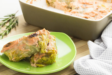 Cabbbage rolls under cream sauce in a ceramic baking dish.