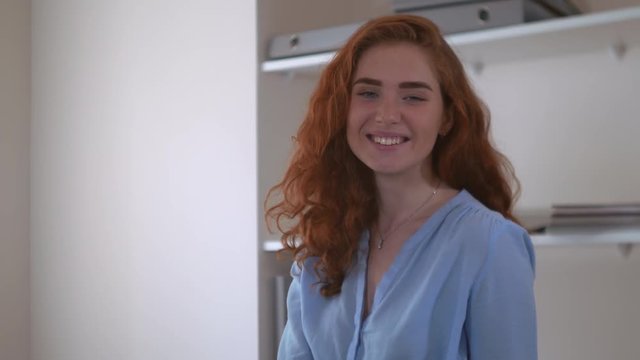 Portrait redhead young woman wearing in casual blue shirt posing looking at he camera smiling.