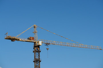 Tower crane on construction site against blue sky.