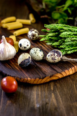 Asparagus and quail eggs on wooden board.