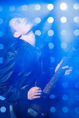 young rock musician playing electric guitar and singing. Rock star on background of spotlights