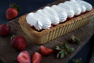 berry tartlet with meringue and strawberries. on a wooden Board