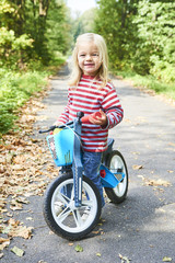Child riding balance bike. Kid on bicycle in sunny park. Little girl ride glider bike on warm summer day. Preschooler learning to balance on run bicycle. Sport for kids