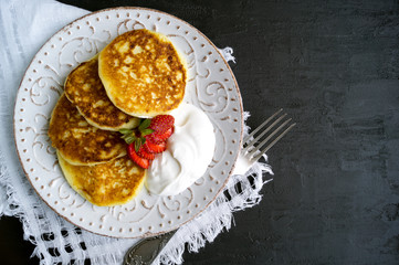 Cottage cheese pancakes with sour cream and strawberries.