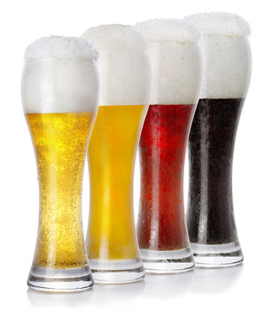 Four glasses of different fresh foamy beer