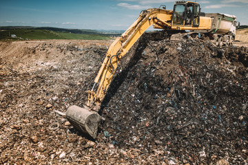 Fototapeta premium Industrial machinery excavating garbage. Close up of heavy duty excavator using scoop and working