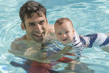 7 month old baby boy playing with dad in pool at swim class