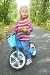 Child riding balance bike. Kid on bicycle in sunny park. Little girl ride glider bike on warm summer day. Preschooler learning to balance on run bicycle. Sport for kids