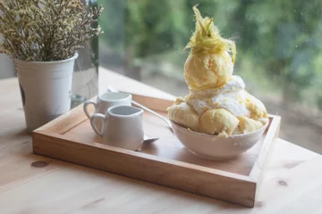 Schilderijen op glas Bingsoo or Bingsu ( Korea dessert) durian served with sweetened condensed milk topping with cotton candy on table near the window © KanitChurem