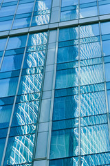 Obraz premium Reflection in blue glass wall of modern office building. Tint blue