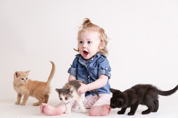 Cute toddle girl plays with baby kittens