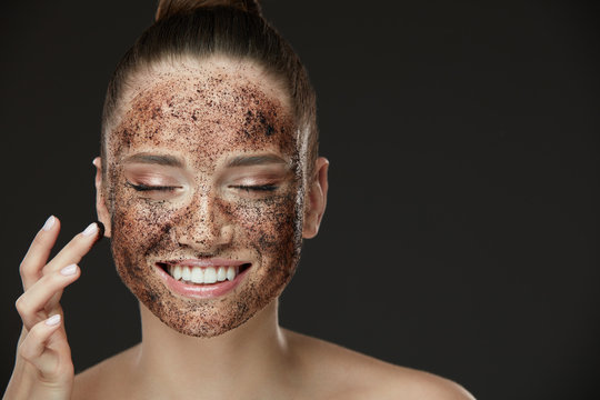 Face Skin Scrub. Smiling Girl Applying Coffee Mask Scrub On Skin