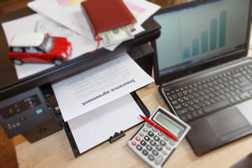 Homeowner and car Insurance form with Laptop, Printer, pen, notebook, calculator on the table
