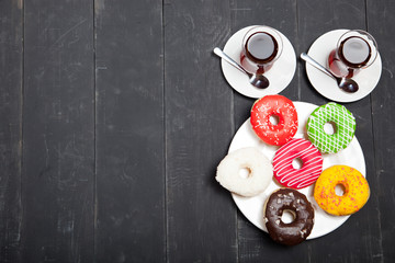 Cups of tea and donuts on a black wooden background