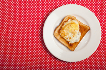 Toast and egg on a plate on a red table