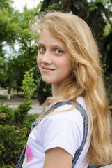 Fototapeta premium Beautiful smiling girl posing over green summer background