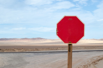 Red stop sign along the road in desert