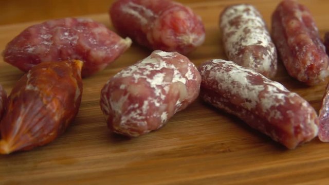 Fork takes one piece from a bunch of jerked sausagesfrom a wooden board