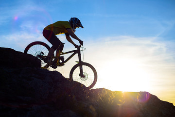Fototapeta na wymiar Silhouette of Cyclist Riding Down the Mountain Bike on Rocky Hill at Sunset. Extreme Sport Concept.