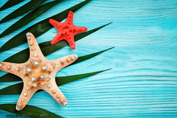 Starfish and palm leaves lying on a blue wooden background . There is a place for labels.