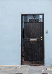 Black Door On Light Blue Stucco Wall