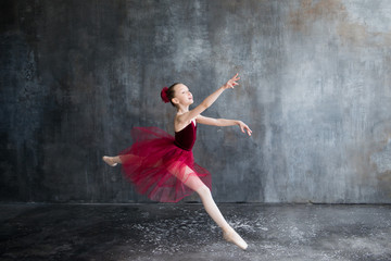 Fototapeta na wymiar girl ballerina in red tutu doing exercise