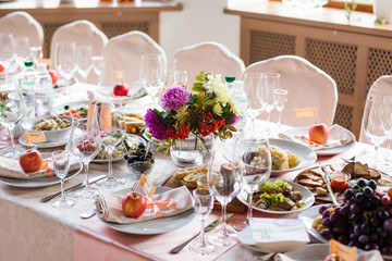 Beautifully decorated banquet table with flowers and different food snacks and appetizers with sandwich, wine glass, plate, apple on corporate event or wedding celebration