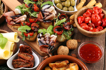 Italian antipasti wine snacks set. Cheese variety, Mediterranean olives, pickles, Prosciutto di Parma, tomatoes, artichokes and wine in glasses