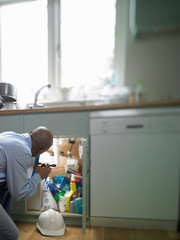 Man repairing plumbing under sink