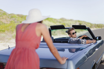 Woman pushing car as boyfriend steers