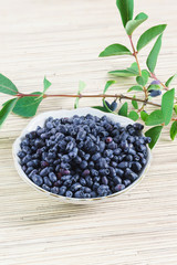 Blue ripe honeysuckle in the Cup and the twig on the table