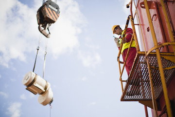 Worker directing crane on oil rig