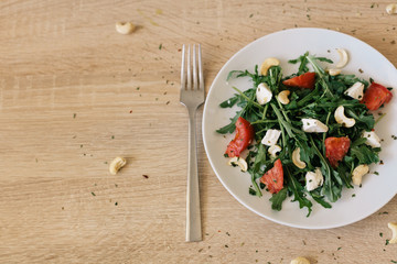 fresh salad with tomato, feta cheese, arugula, cashew on the wooden table