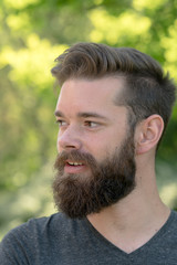 Fascinating guy with beard in park. Vertical portrait