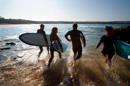 Four People Running Into The Water