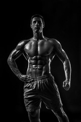 Naklejka na ściany i meble Muscular and fit young bodybuilder fitness male model posing ove