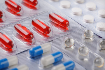 Red vitamin pills in plastic bag with other pills