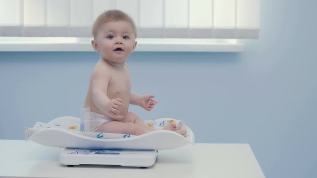 Adorable little boy sits on the weigher
