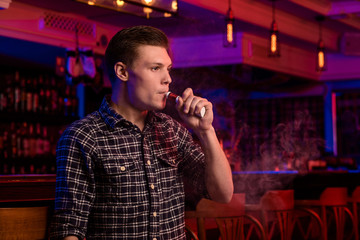 The man smoke an electronic cigarette at the vape shop.
