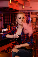 Young pretty woman smoke an electronic cigarette at the vape bar