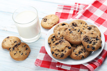 Chocolate chip cookies with glass of milk on white wooden table